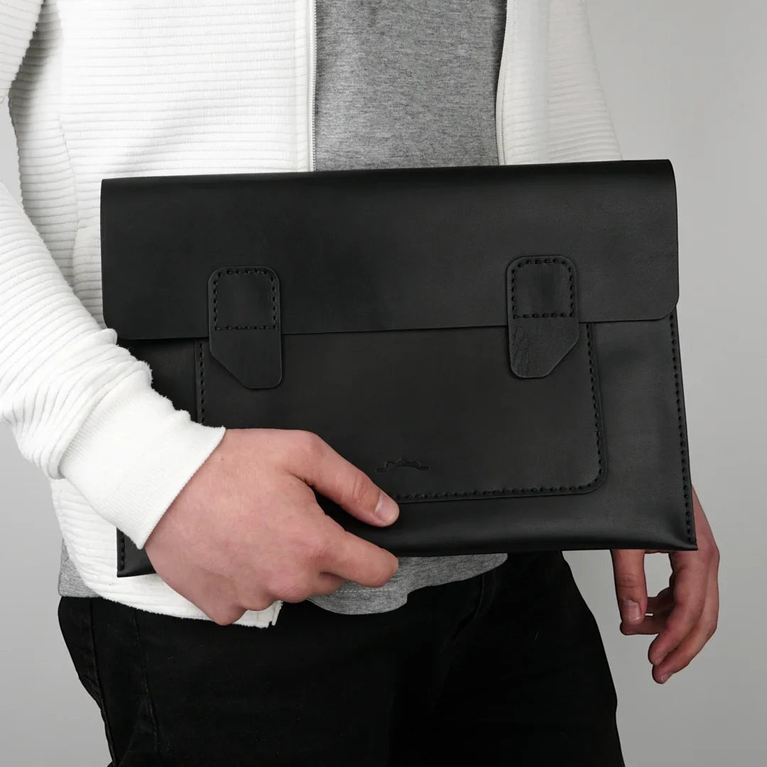 MODISTIAZ black leather document folio with snap closure and exterior pocket, held by a person.