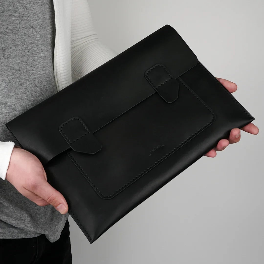 MODISTIAZ black leather document folio with snap closure and exterior pocket, held by a person.