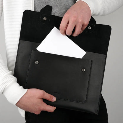 MODISTIAZ black leather document folio with exterior pocket and snap closure, held by a person.